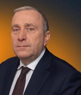 Grzegorz Schetyna podczas spotkania z wyborcami, uśmiechnięty i gestykulujący, w tle widoczny tłum i transparenty.