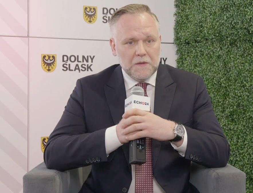 Dawid Jackiewicz przemawiający z mównicy podczas wiecu lub konferencji, gestykulujący z przekonaniem.