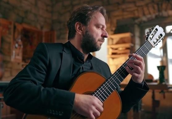 Zbliżenie na klasyczną gitarę, ukazujące detale instrumentu w ciepłym świetle.