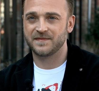 Mateusz Gessler w kuchni, skupiony na przygotowywaniu potrawy, z widocznymi narzędziami kulinarnymi.