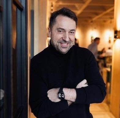 Marcin Miller w swobodnej pozie, uśmiechnięty, w otoczeniu sugerującym jego spokojne życie w Ełku.