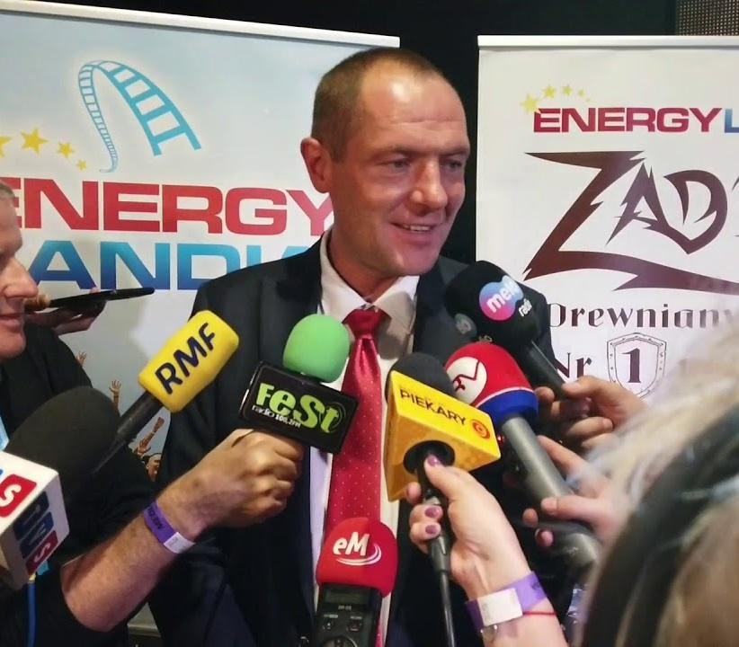 Marek Goczał za kierownicą rajdowego pojazdu SSV, pędzący po piaszczystym torze, uosabiający dynamikę i pasję do sportów motorowych.