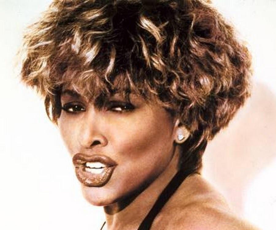 Tina Turner w pełnej krasie na scenie, w trakcie porywającego występu, w charakterystycznym stroju i z burzą włosów, ukazująca swoją energię i charyzmę.