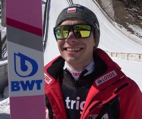 Jakub Wolny w locie podczas skoku narciarskiego, z widoczną determinacją i techniką, na tle zimowego krajobrazu skoczni.